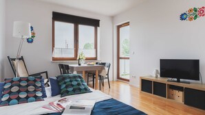 Een moderne slaapkamer met een bed, een televisie, een eethoek en een balkon.