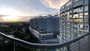 A high-rise building with multiple balconies and a view of a sunset over a cityscape. - Room with a sea and city view!!  (Lapu Lapu)