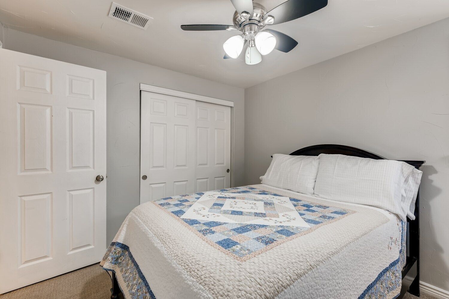 A bedroom with a bed, a ceiling fan, and white doors.
