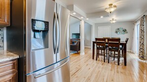 Una cocina moderna con refrigerador de acero inoxidable, armarios de madera y un área de comedor con mesa y sillas.
