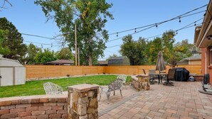 Un patio trasero con muros de piedra, una parrilla y mobiliario exterior.