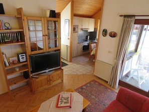 A cozy living room with a television, wooden shelves, and a red sofa.