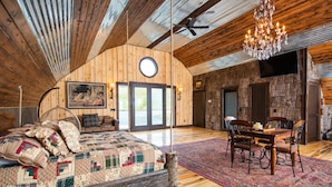 A spacious loft bedroom with a large bed, a dining area, and a chandelier.