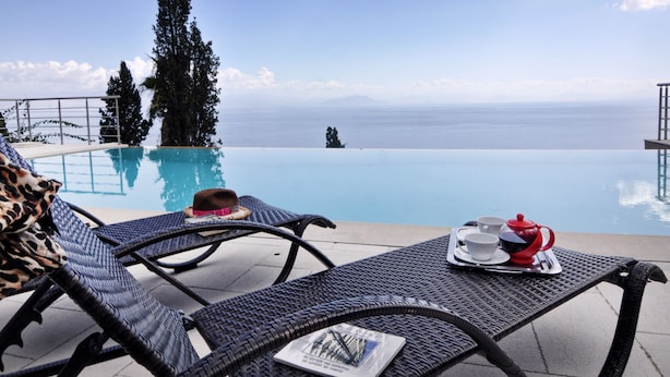 A poolside area with lounge chairs, a table with a tray of tea and cups, and a view of the sea. - Edem (Corfu)