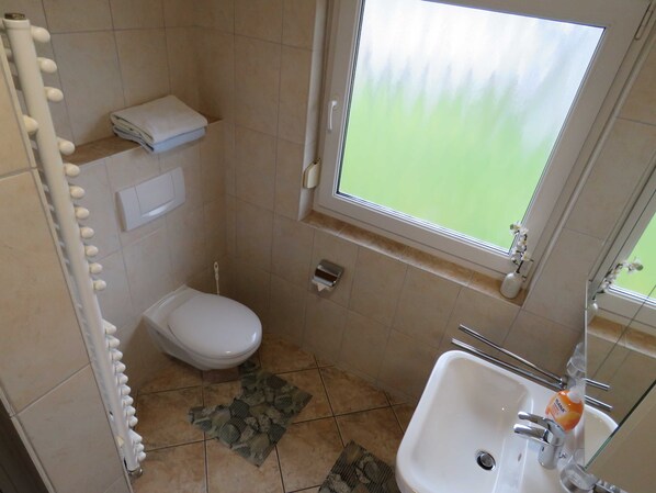 A small bathroom with a toilet, sink, and a window.