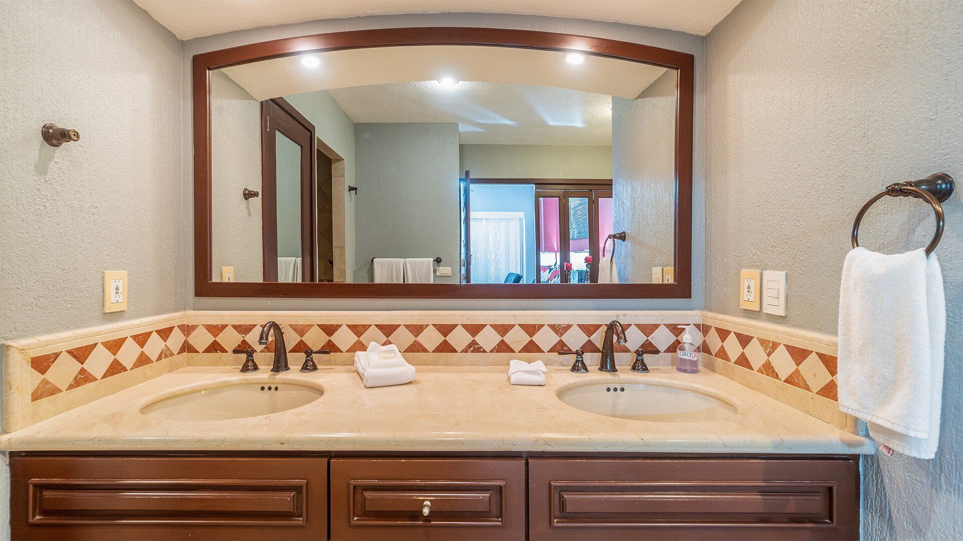 A bathroom with two sinks, a large mirror, and a towel rack.