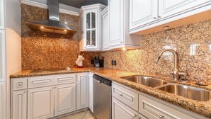 A kitchen with granite countertops, stainless steel appliances, white cabinetry, and a double sink.
