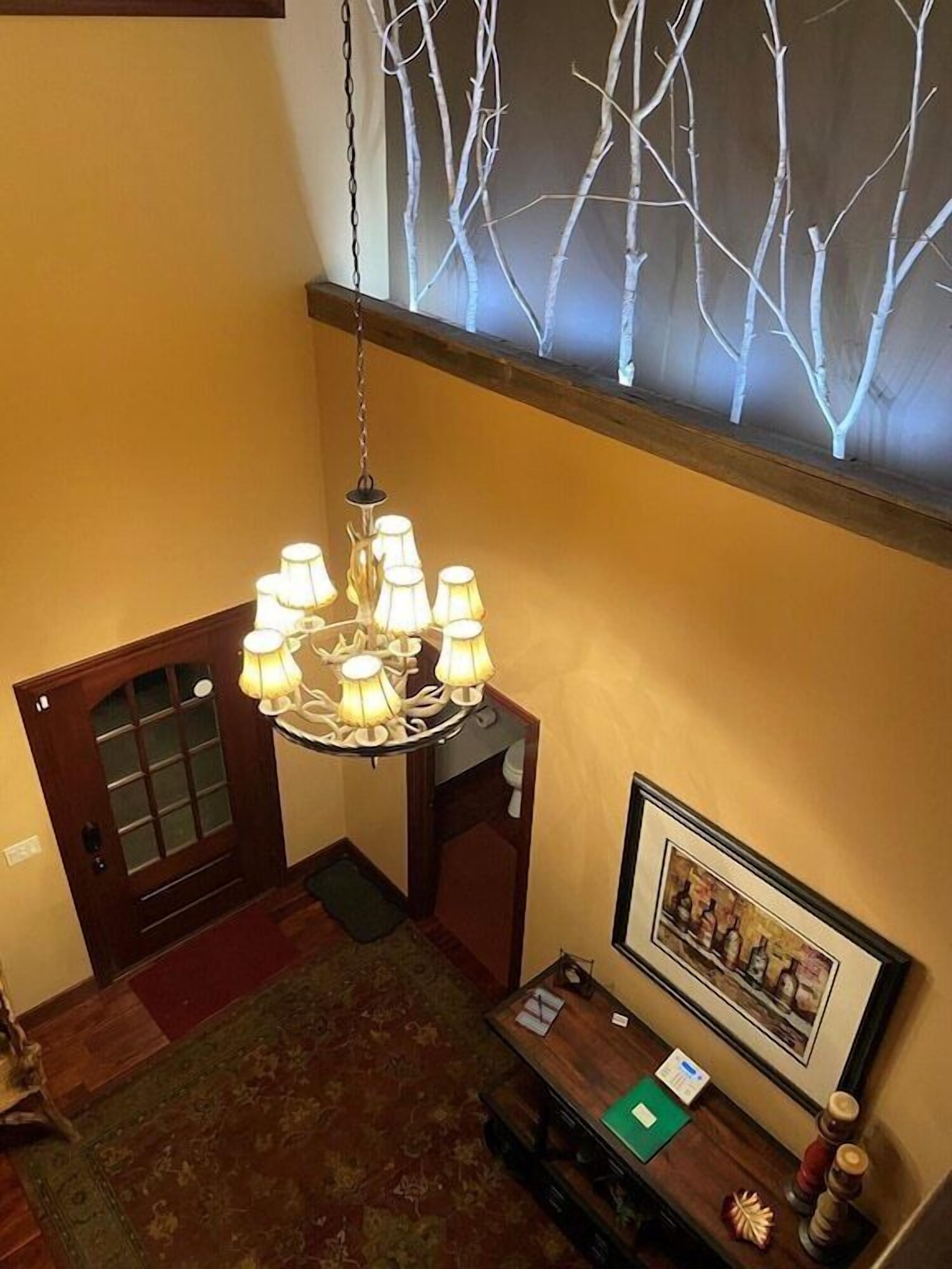 Un lustre dans un coin, un tableau encadré au mur et un banc en bois avec un tapis.