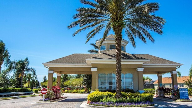 A gazebo-style building with a tiled roof, surrounded by landscaped gardens and palm trees.