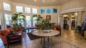 A spacious lobby with a round table, sofas, and potted plants.