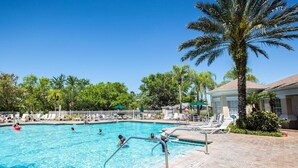 A swimming pool with lounge chairs and palm trees.