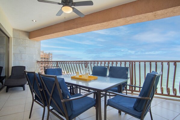 A balcony with a table and chairs, a ceiling fan, and a view of the sea. - Sonoran Sun W-806 Chasing The Sun Great Oceanfront Condo (Puerto Peñasco)