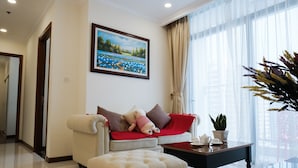 Una sala de estar con un sofá, un reposapiés y un cuadro en la pared.