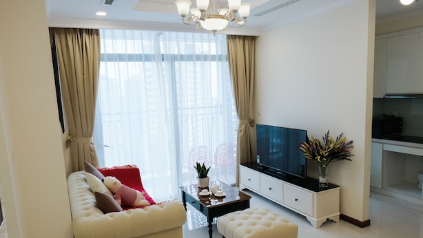 Una sala de estar moderna con sofá, reposapiés y televisor sobre un mueble.