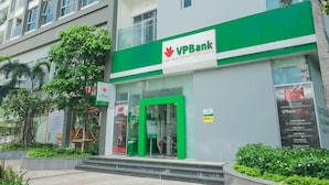 Un edificio bancario con fachada verde y blanca, un cajero automático y un cartel que indica una tasa de interés del 7,2% para cuentas de ahorro.