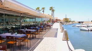 Un restaurante frente al agua con terraza al aire libre que da a un puerto deportivo.