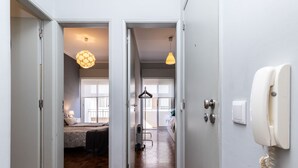 Un pasillo con piso de madera que conduce a un dormitorio con cama y una lámpara colgante.