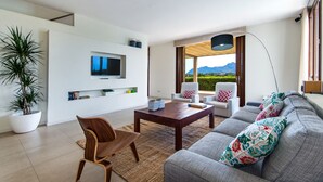 A modern living room with a flat-screen TV, a sofa, a coffee table, and a chair. - Luxury villa for 10 with pool, gym, AC and wifi, only 150m to the sea  (Alcúdia)