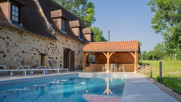 A swimming pool with lounge chairs, a covered seating area, and a stone building with a tiled roof. - Pool Escape in Saint-Laurent (Saint-Laurent-la-Vallée)