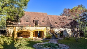 A rustic stone building with a sloped roof, a covered entrance, and a small staircase leading to the main entrance. - Pool Escape in Saint-Laurent (Saint-Laurent-la-Vallée)