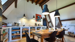 A spacious kitchen with wooden beams, a dining table set for four, and a wine rack. - Pool Escape in Saint-Laurent (Saint-Laurent-la-Vallée)