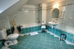 A bathroom with a bathtub, toilet, and sink, featuring a green and white tile design.