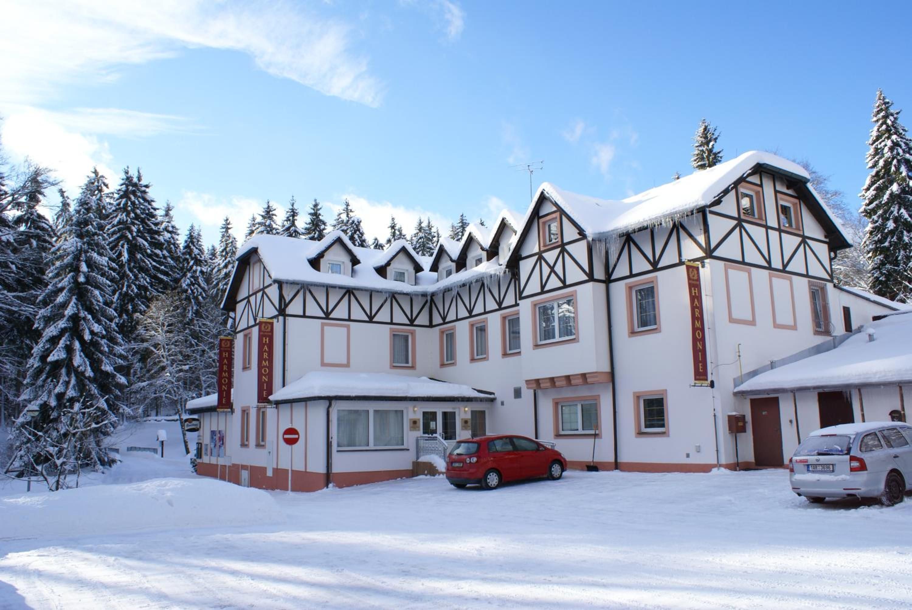 Un edificio grande de varios pisos con un estilo arquitectónico tradicional, que presenta una fachada simétrica y un techo cubierto de nieve.