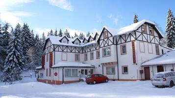 Un edificio grande de varios pisos con un estilo arquitectónico tradicional, que presenta una fachada simétrica y un techo cubierto de nieve.
