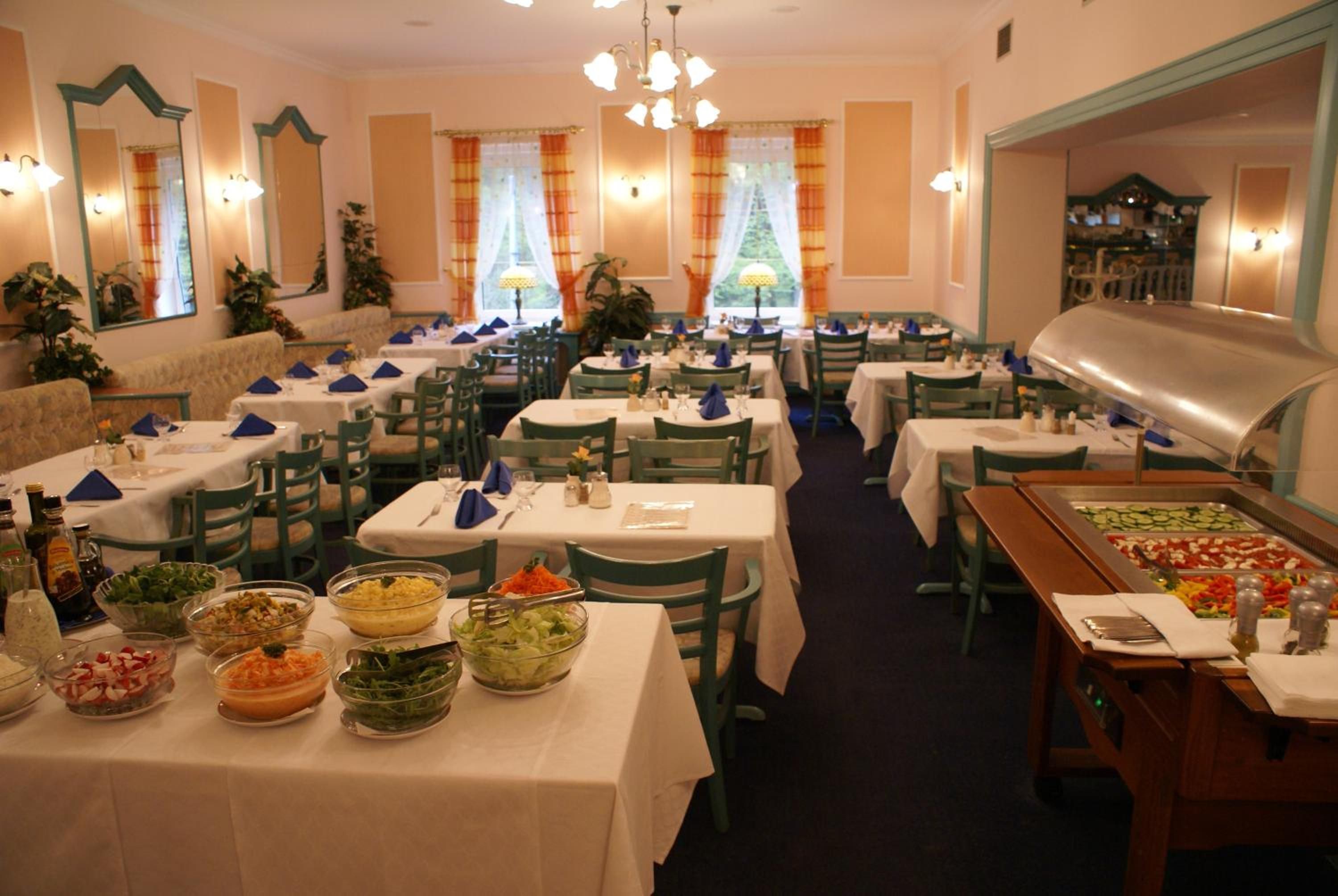 A restaurant with multiple tables, chairs, and a buffet area with various dishes.