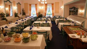 A restaurant with multiple tables, chairs, and a buffet area with various dishes.