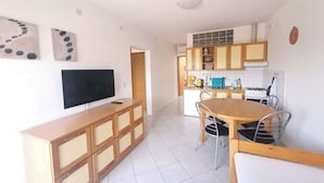 Una cocina moderna con armarios de madera, horno empotrado y comedor con mesa y sillas de madera.