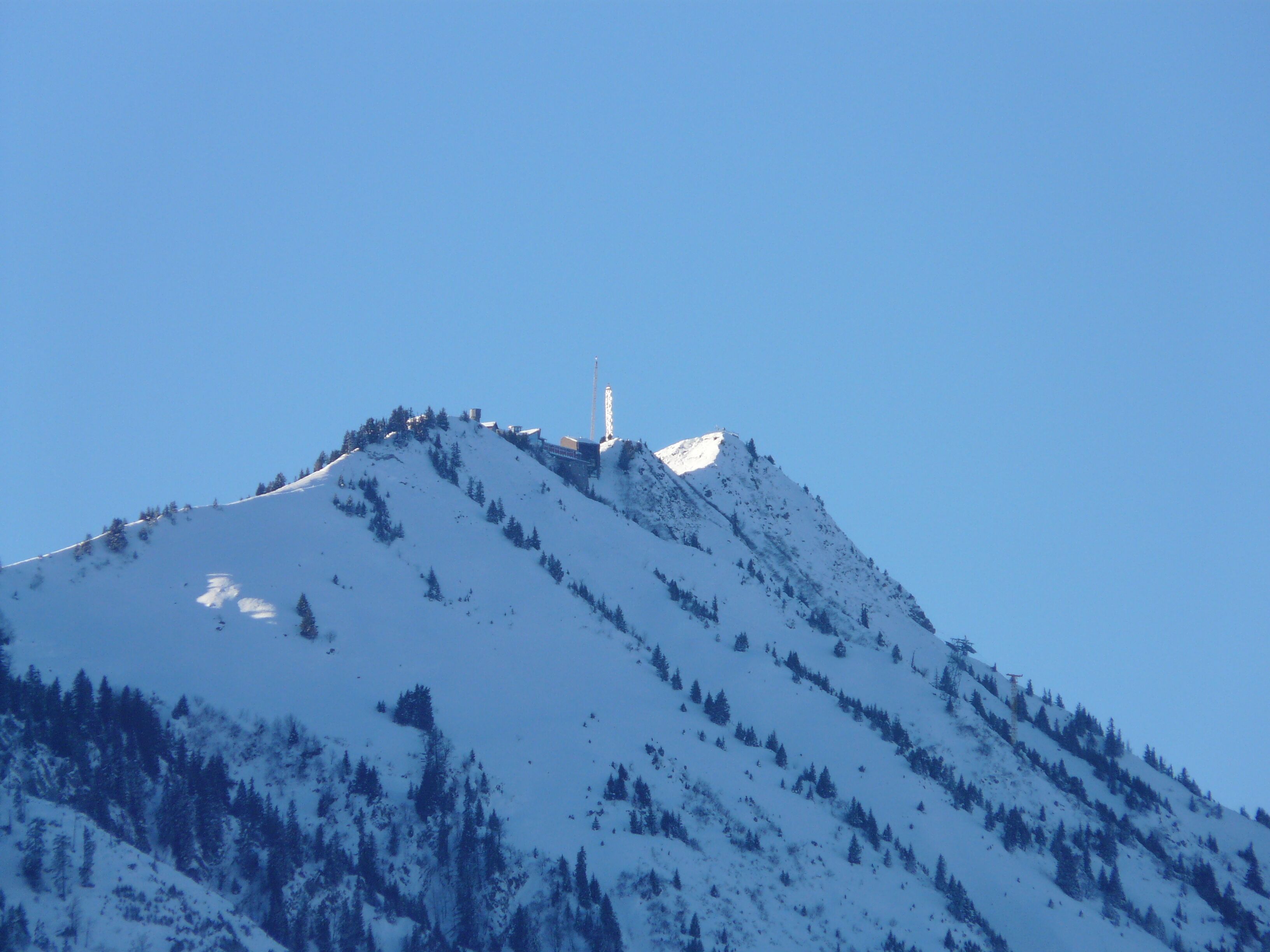 Una montaña cubierta de nieve con una torre alta en la cima.
