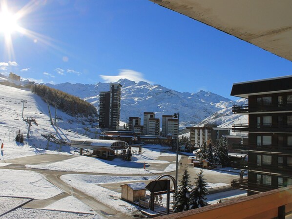 A ski resort with snow-covered slopes, a ski lift, and buildings with mountain views.