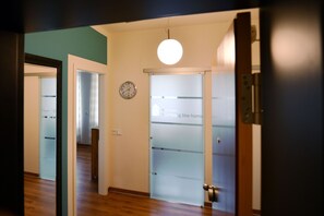 A hallway with a frosted glass door, a clock, and a hanging light fixture. - Apartment Nuremberg Like Home (Mitte)