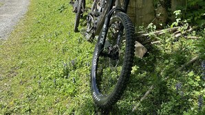 Un bâtiment rustique en bois, doté d’un mur en pierre, d’un chemin de gravier et de vélos garés devant.