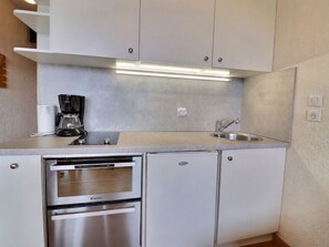 A compact kitchen with a built-in oven, a coffee maker, and a sink.