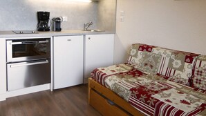A compact kitchen with a built-in oven, a coffee maker, and a sink.