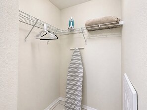 A laundry area with a hanging rack, an ironing board, and a towel.