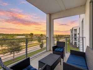 A balcony with wicker furniture, a view of a building, and a sunset. - Amazing stay/Waterpark/Near Disney (Kissimmee)