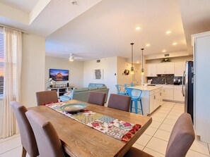 A modern living space with a dining area, kitchen, and a television displaying a scenic view. - Amazing stay/Waterpark/Near Disney (Kissimmee)