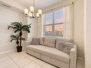 A living room with a beige sofa, a potted plant, and a window with blinds. - Amazing stay/Waterpark/Near Disney (Kissimmee)