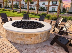 A circular stone fire pit with seating around it, set in a paved area with a residential backdrop. - Amazing stay/Waterpark/Near Disney (Kissimmee)