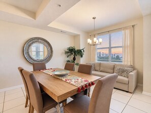 A dining area with a wooden table, chairs, a decorative mirror, and a sofa with a view of the cityscape. - Amazing stay/Waterpark/Near Disney (Kissimmee)