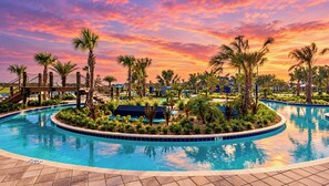 A pool surrounded by palm trees and a wooden bridge, with a sunset sky in the background. - Amazing stay/Waterpark/Near Disney (Kissimmee)