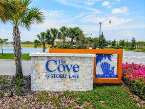 Placa para 'The Cove at Storey Lake', com uma palmeira e um lago ao fundo.