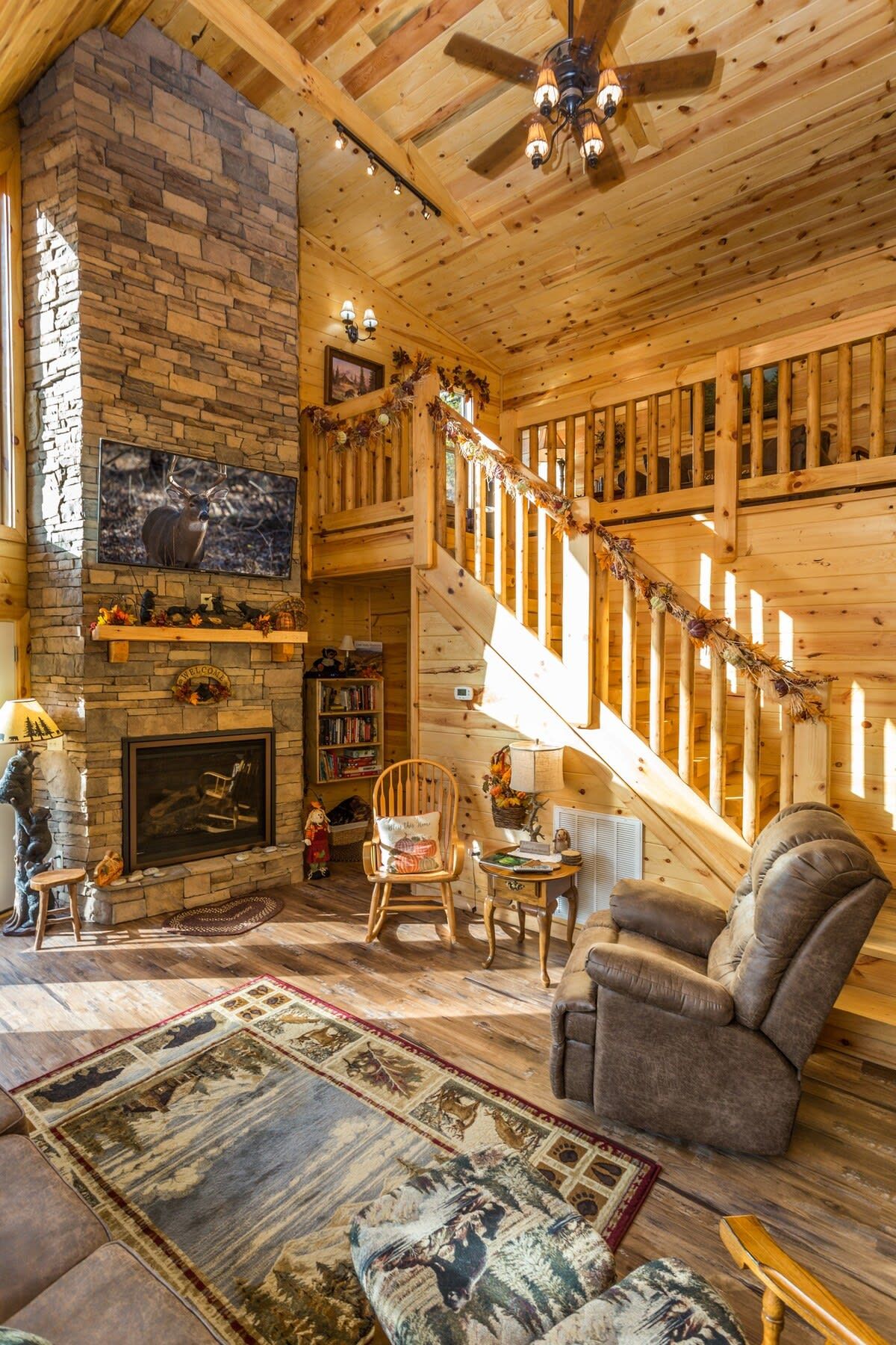A wooden interior with a fireplace, a staircase, and a cozy seating area.