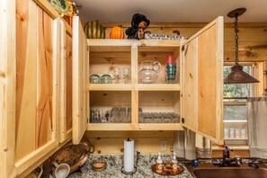 Interior de una cabaña de madera con cocina, que incluye una encimera de granito, un lavabo y armarios de madera.