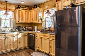 A kitchen with wooden cabinets, a stainless steel refrigerator, and a granite countertop.