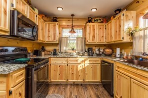 Cocina con armarios de madera, un microondas de acero inoxidable y encimeras de granito.