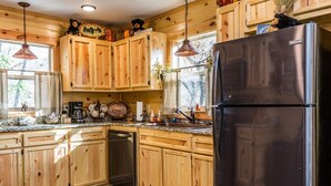 Una cocina con armarios de madera, un refrigerador de acero inoxidable y una encimera de granito.